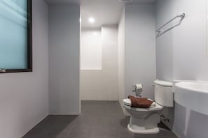 Un baño con inodoro, lavamanos y un perchero para toallas.