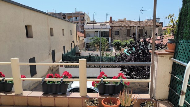 Een balkon met bloempotten en uitzicht op de stad.