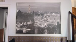 Een zwart-wit foto van een stadsgezicht met een opvallende toren, waarschijnlijk de Eiffeltoren, en een rivier met bruggen.