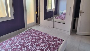 Een slaapkamer met een bed, een garderobe en een spiegel.