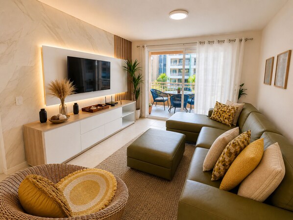Una sala de estar moderna con una televisión de pantalla plana, un conjunto de sofás y un comedor con sillas azules.