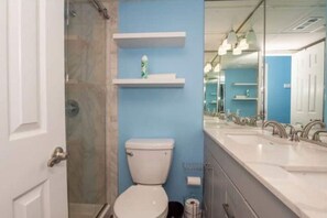 A bathroom with a toilet, a shower, and a sink area with mirrors.