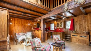 A rustic wooden interior with a dining area, kitchen, and seating.