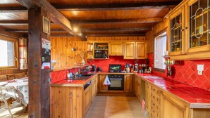 A wooden kitchen with a red backsplash, wooden cabinets, and a central island.