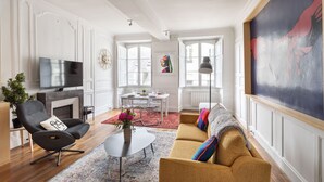 Un salón amplio con un sofá moderno, televisión y un comedor con mesa y sillas.