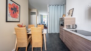 A modern kitchen with a dining area, featuring a kitchen island, built-in oven, and a coffee maker. - Le Jardin des Docks - Appt avec jardin (Lyon)