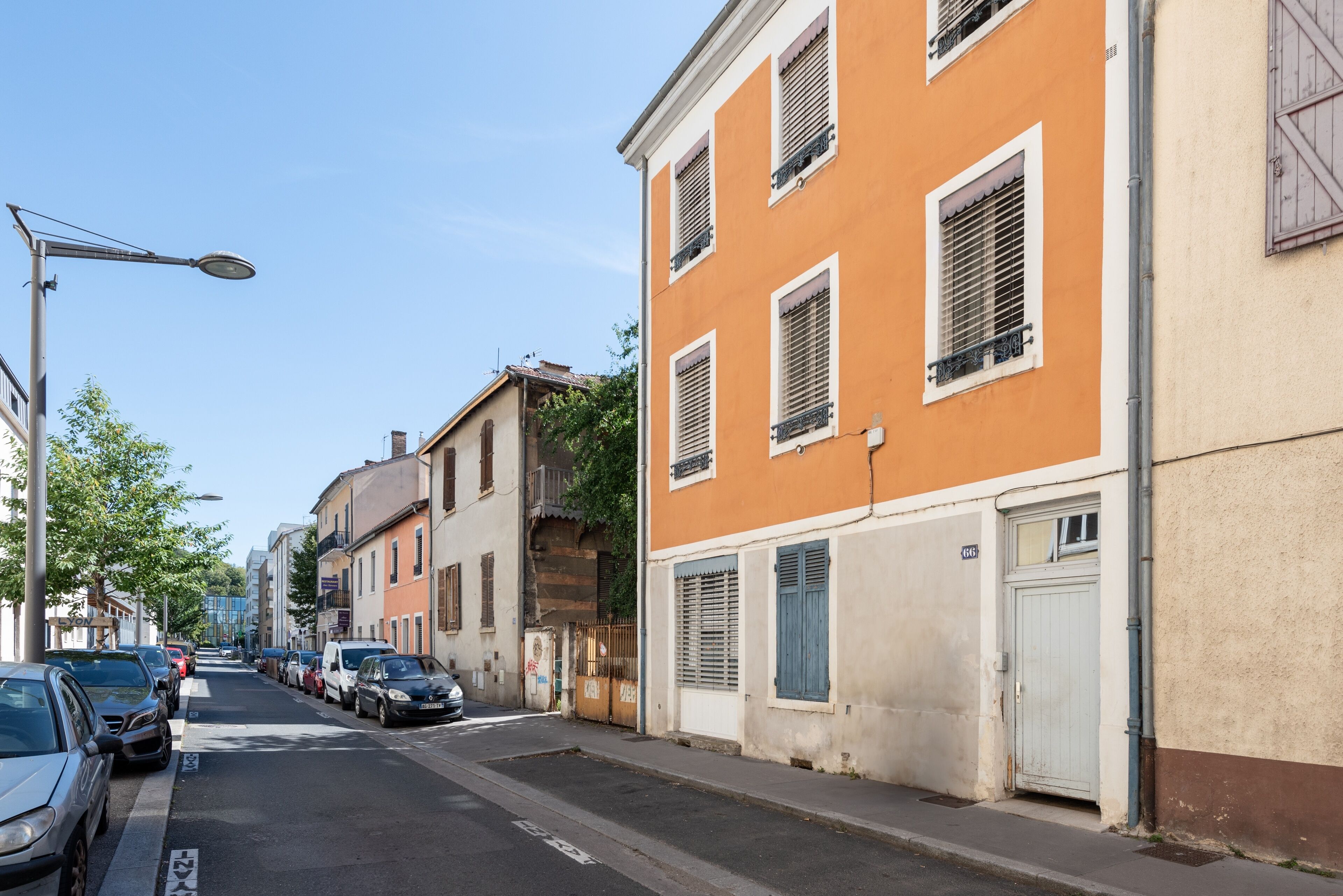 Une rue bordée de voitures garées et d’immeubles.