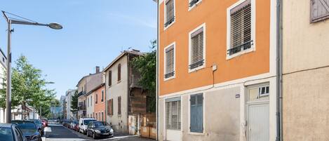Une rue bordée de voitures garées et d’immeubles.