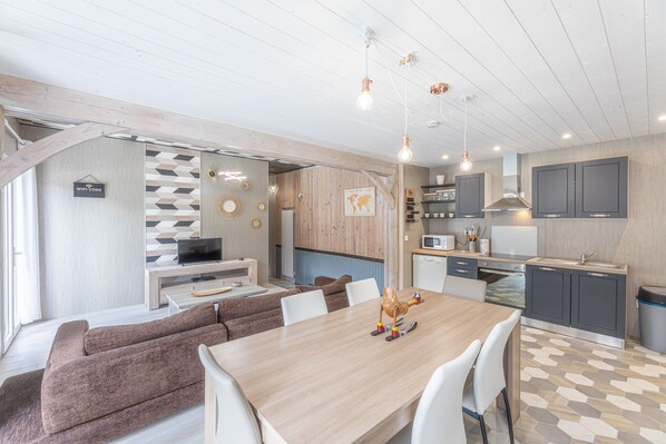 A modern kitchen with a microwave, stove, and cabinets. There is a dining area with a table and chairs.