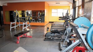 Une salle de sport équipée de divers appareils d’exercice, notamment des tapis de course et des appareils de musculation.