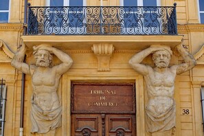 Eine Gebäudefassade mit einem Schild, auf dem 'Tribunal de Commerce' steht, und einem Balkon mit aufwendiger Metallverzierung.
