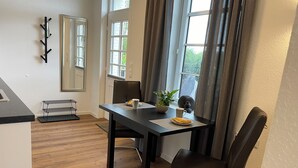 Spiseplads med bord, stole, en plante og et vindue med gardiner.