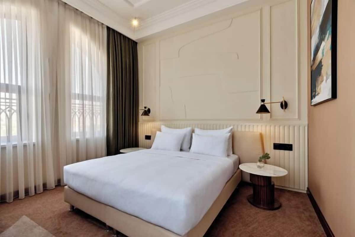 A hotel room with a large bed, a round table, and a nightstand.