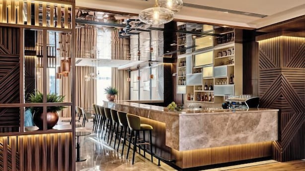 A modern bar area with a marble countertop, bar stools, and a decorative wall with geometric patterns. - Crowne Plaza TASHKENT by IHG (Tashkent)