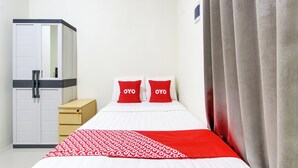A hotel room with a bed, two red pillows with "OYO" text, a wardrobe, and a curtain. - OYO 92477 Anugrah Kostel Syariah (Semarang)