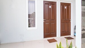 A building with two numbered doors, a window, and a tiled entrance area with doormats. - OYO 92477 Anugrah Kostel Syariah (Semarang)