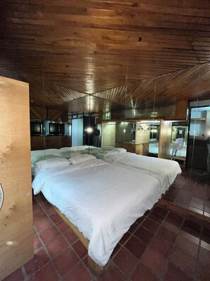 Una habitación con dos camas, techo de madera y suelo de ladrillo.