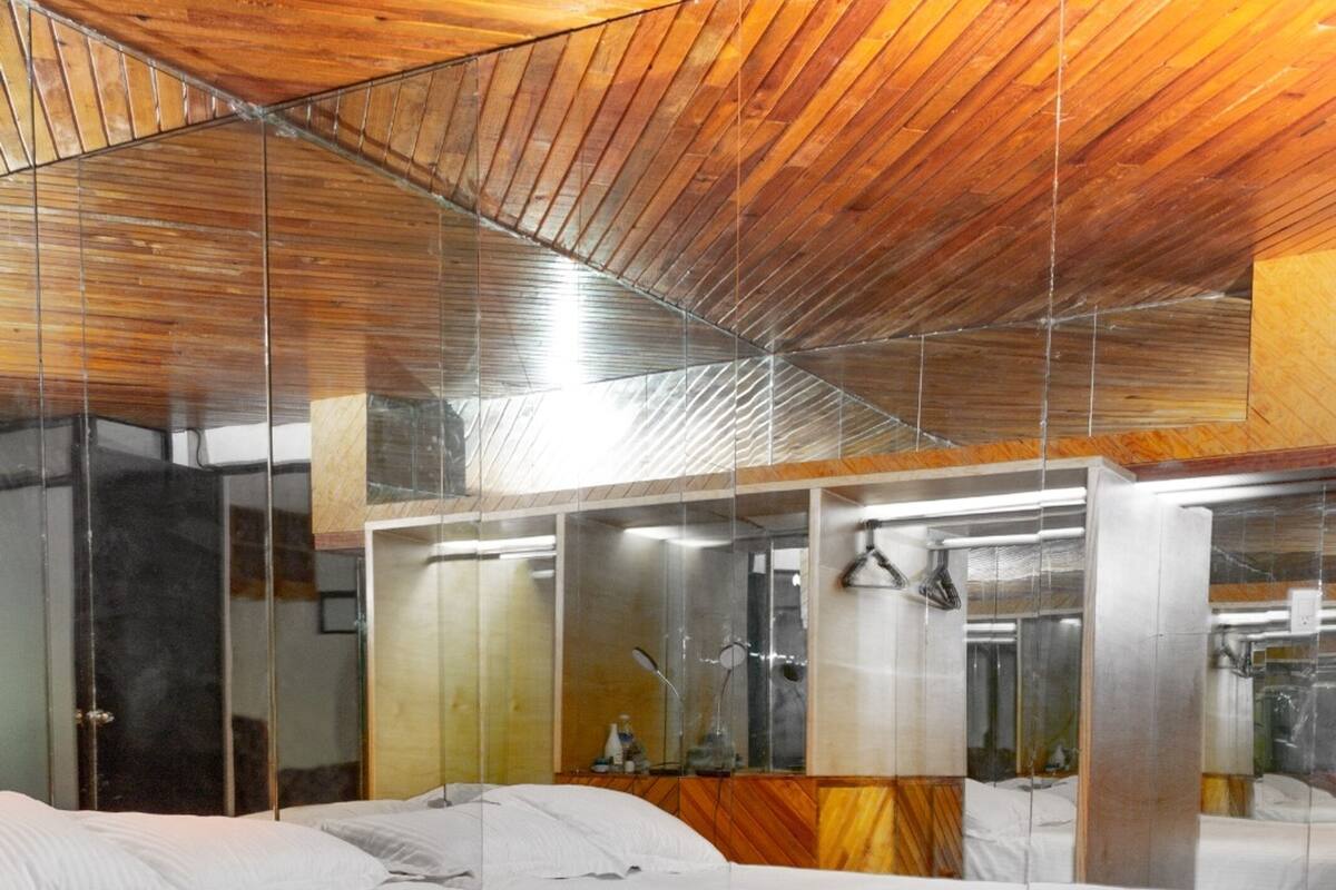 Une chambre d’hôtel avec un grand lit, un plafond en bois et un sol recouvert de carreaux rouges.