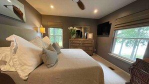 A bedroom with a large bed, a dresser, a ceiling fan, and windows with a view of trees. - House on Smith Lake! No steps to water/dock! 4 bedrooms & 3 full baths. (Jasper)