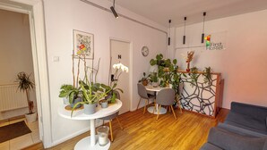 Een moderne woonkamer met een grijze bank, een eethoek met een witte tafel en stoelen, en een decoratief wandpaneel.