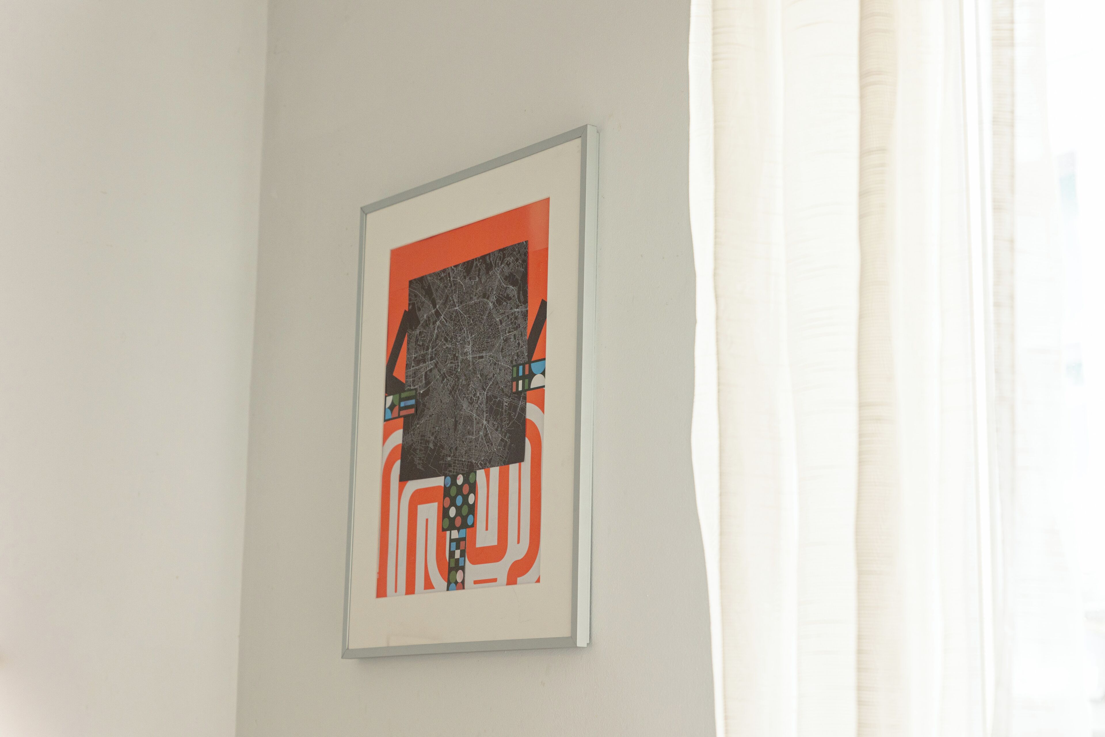Une œuvre d’art abstraite encadrée, accrochée à un mur uni.