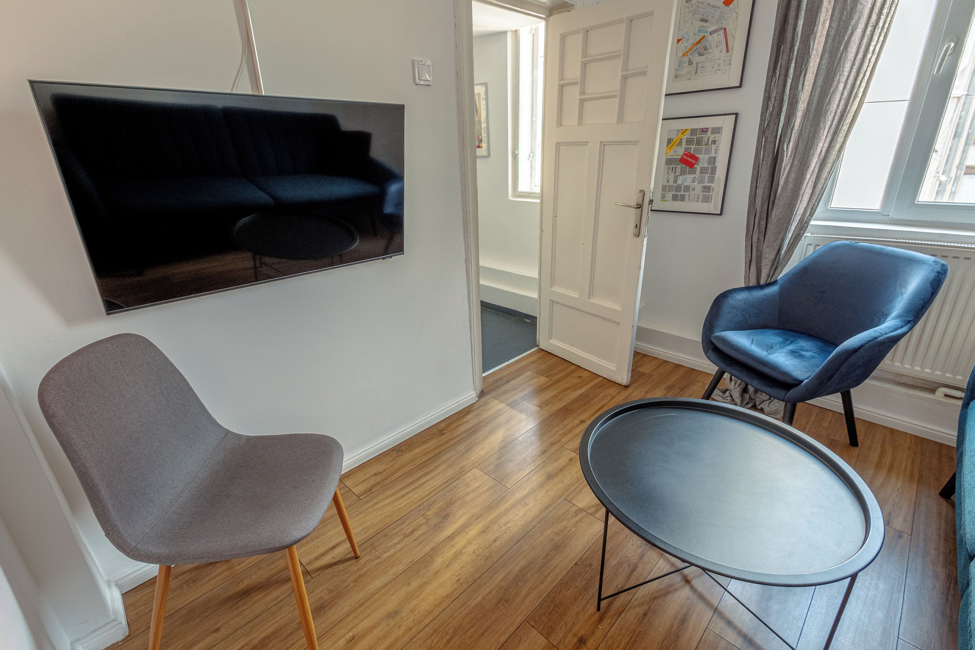 Una habitación con un sofá azul oscuro, un sillón gris y una mesa redonda.