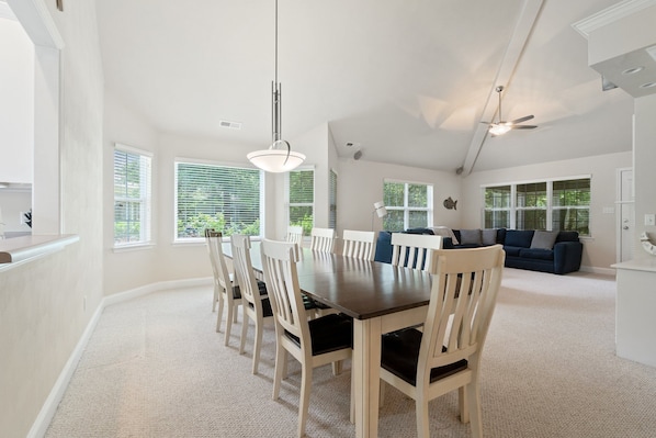 A spacious dining area with a long table and chairs, a dark wooden table, a ceiling fan, and a sofa in the background. - Spacious 4BR Coastal Retreat in Bay Creek – Beach & Golf (Cape Charles)
