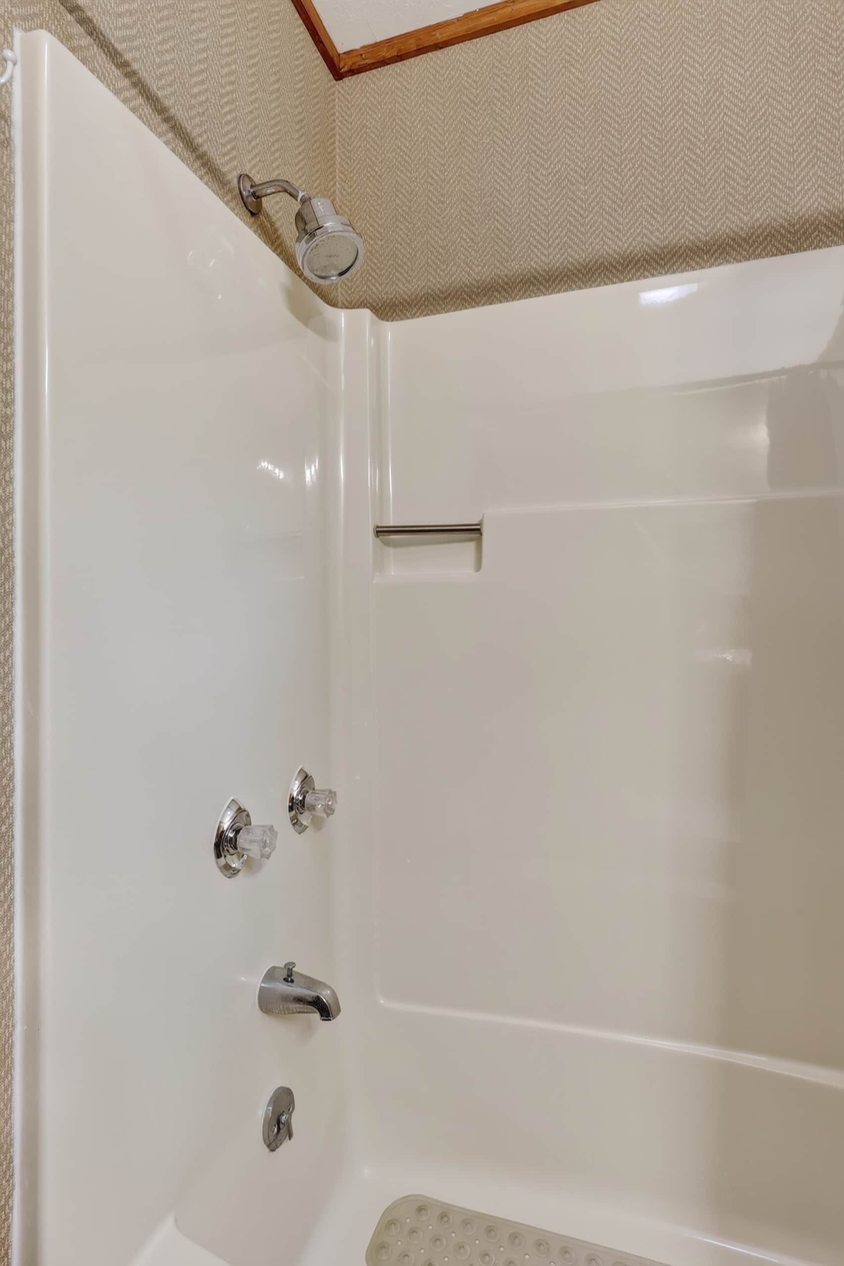 Una bañera blanca con ducha y dos llaves.