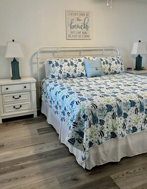 Ein Schlafzimmer mit einem Bett, Nachttischen, einer Wanduhr und einem motivierenden Zitat.