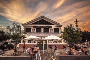 A building with a sign reading "St. Roch Market" and outdoor seating with umbrellas.