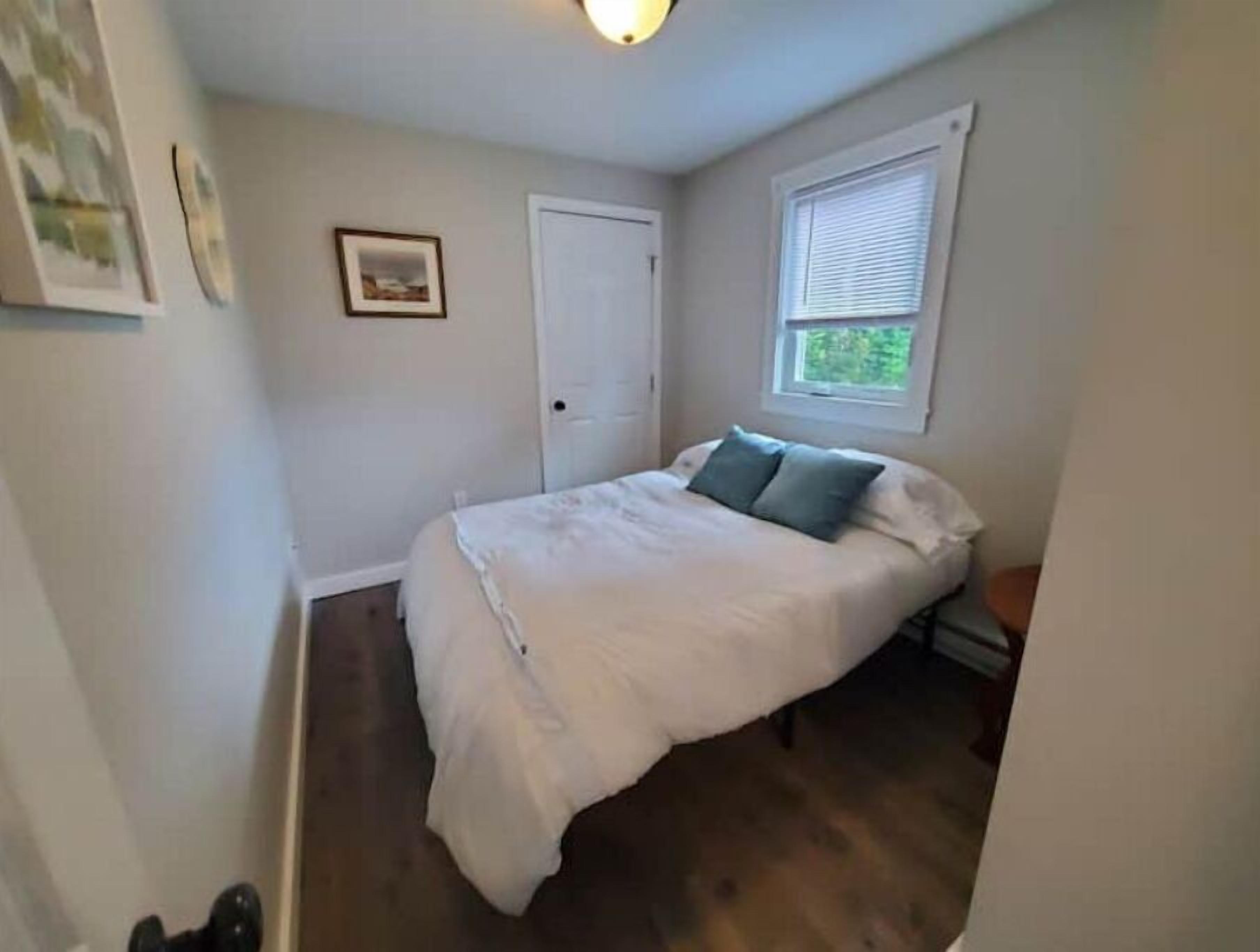A bedroom with a bed, a window, and a door.
