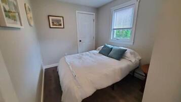 A bedroom with a bed, a window, and a door.