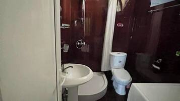 Un baño pequeño con lavamanos, inodoro y ducha.