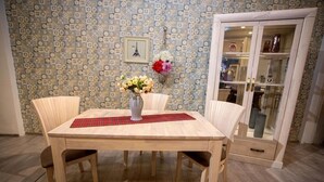 Un coin repas avec une table en bois, quatre chaises, un vase de fleurs et un papier peint à motifs représentant la Tour Eiffel.