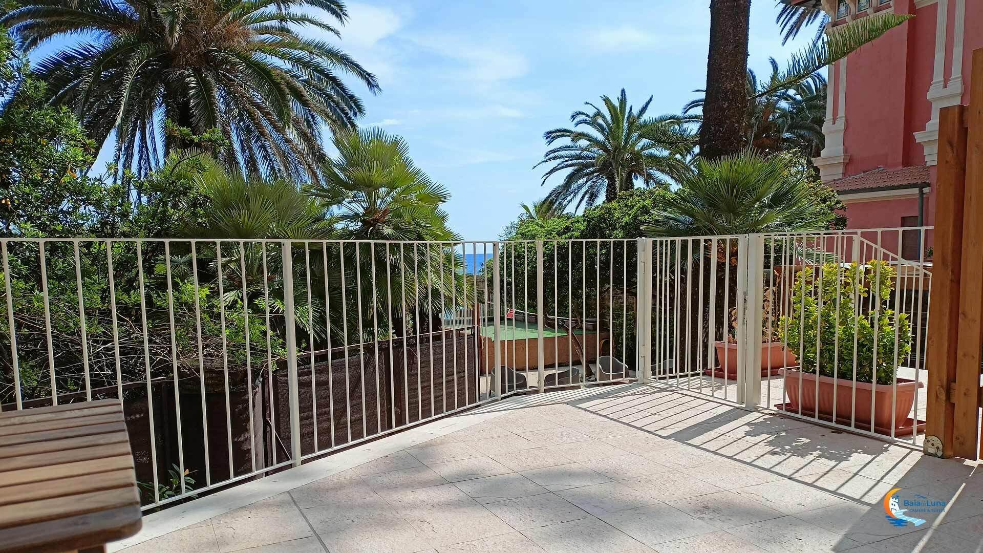 Un área exterior cerrada con palmeras y un edificio al fondo.