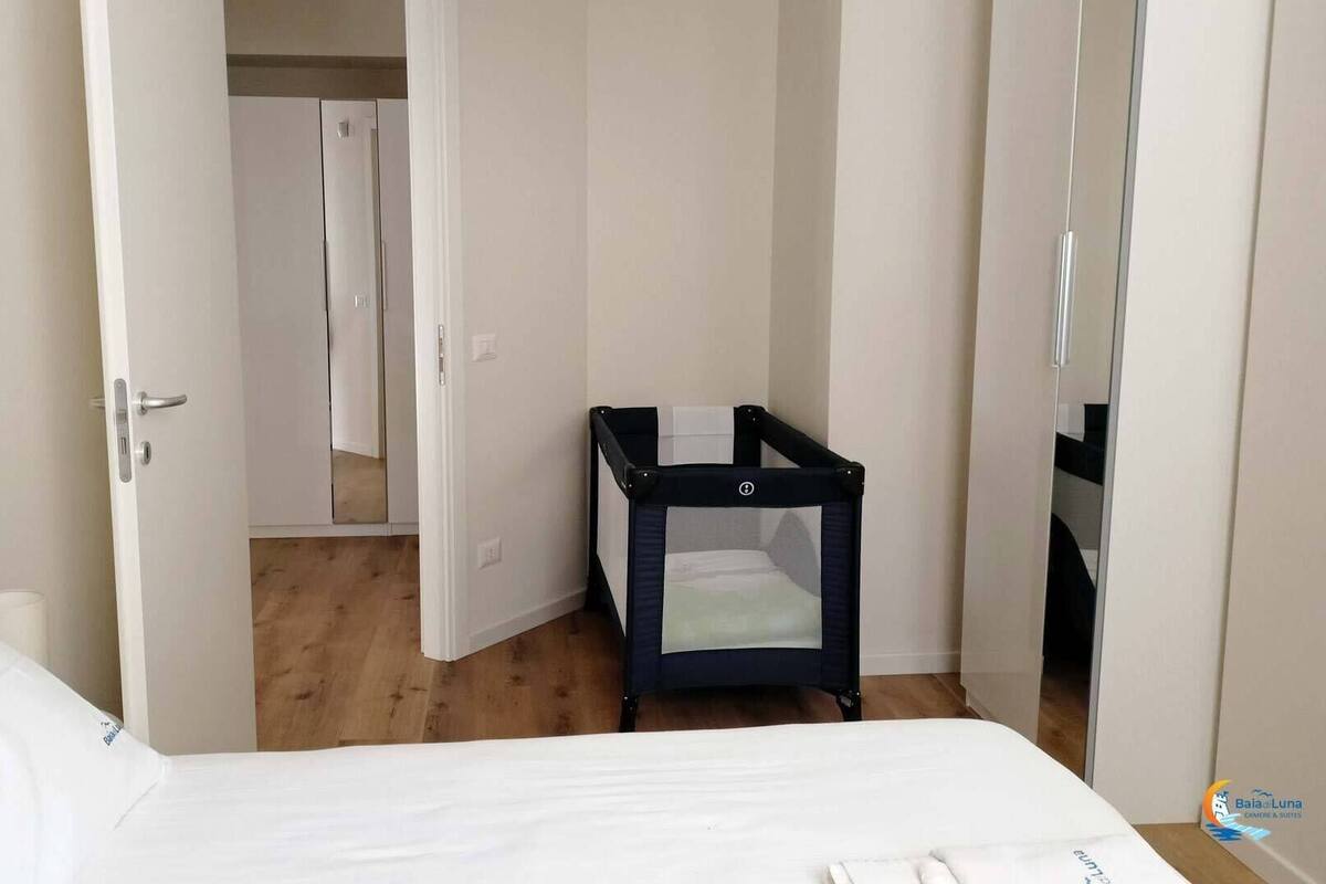 Ein Hotelzimmer mit einem Bett, einem kleinen schwarzen Babybett und Holzboden.