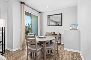 A dining area with a round table, four chairs, a mirror on the wall, and a bookshelf.