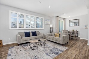 A living room with two sofas, a coffee table, and a dining area with a table and chairs.