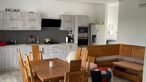 A modern kitchen with grey cabinets, a dining table with wooden chairs, and a built-in seating area with a bench. - Impeccable Luxury 3-bed Apartment in Albion (Albion)
