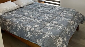 A bedroom with a wooden headboard, a floral-patterned bedspread, and two windows with horizontal blinds. - Impeccable Luxury 3-bed Apartment in Albion (Albion)