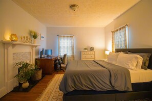 Une chambre à coucher comprenant un lit, un bureau, une chaise, une commode et une cheminée.