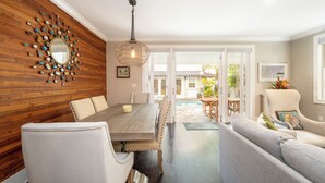 A dining area with a wooden wall, a large mirror, and a hanging light fixture.