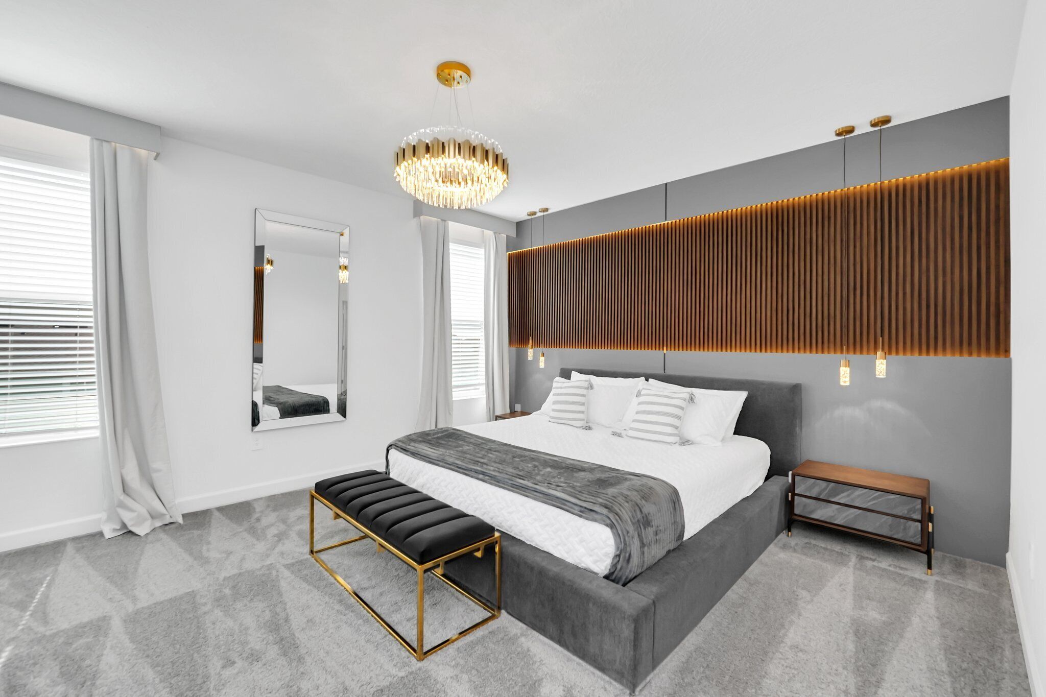 Une chambre moderne avec un grand lit, un banc, un miroir et un revêtement mural au design original.