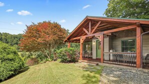 A rustic cabin with a covered porch, a stone pathway, and a well-maintained lawn. - Cozy riverfront cabin on the New River.  Close to Boone and Appalachian State. (Boone)