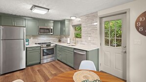 A modern kitchen with green cabinets, stainless steel appliances, and a white tiled backsplash. - Cozy riverfront cabin on the New River.  Close to Boone and Appalachian State. (Boone)