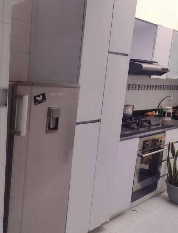 Una cocina moderna con armarios blancos, horno empotrado y campana extractora de acero inoxidable.