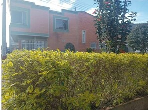 Un edificio de ladrillo de dos pisos con fachada roja, una ventana pequeña y una puerta visible.