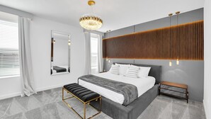 Quarto moderno com cama grande, um banquinho, um espelho e um design de painel de parede único.