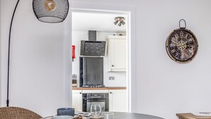 A dining area with a round table, wicker chair, and a small wooden side table. - Stylish Flat Close To Beach - Pass the Keys (Chichester)