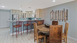 Une cuisine moderne avec un îlot central, des tabourets de bar et une table à manger en bois.